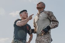 U.S. Marine Corps Martial Arts Instructor, Staff Sgt. Patrick Chok, with Support Battalion, Recruit Training Regiment, instructs a recruit with Lima Company, 3rd Recruit Training Battalion, on how to properly conduct dynamic warm-ups before a Marine Corps Martial Arts Program class at Marine Corps Recruit Depot San Diego, California, Oct. 29, 2024. MCMAP aims to strengthen the mental and moral resiliency of recruits and Marines through realistic combative training, warrior ethos studies, and physical hardening. (U.S. Marine Corps photo by Cpl. Sarah M. Grawcock)