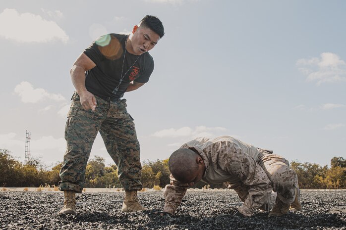 U.S. Marine Corps Martial Arts Instructor, Staff Sgt. Patrick Chok, with Support Battalion, Recruit Training Regiment, instructs a recruit with Lima Company, 3rd Recruit Training Battalion, on how to properly conduct dynamic warm-ups before a Marine Corps Martial Arts Program class at Marine Corps Recruit Depot San Diego, California, Oct. 29, 2024. MCMAP aims to strengthen the mental and moral resiliency of recruits and Marines through realistic combative training, warrior ethos studies, and physical hardening. (U.S. Marine Corps photo by Cpl. Sarah M. Grawcock)
