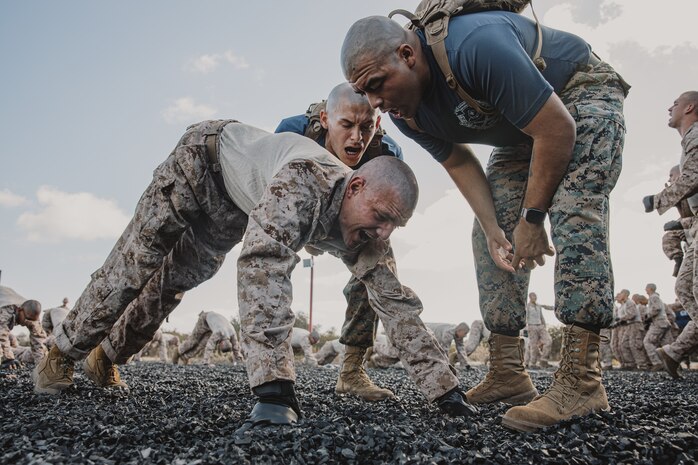 U.S. Marine Corps drill instructors with Lima Company, 3rd Recruit Training Battalion, instruct a recruit during dynamic warm-ups before a Marine Corps Martial Arts Program class at Marine Corps Recruit Depot San Diego, California, Oct. 29, 2024. MCMAP aims to strengthen the mental and moral resiliency of recruits and Marines through realistic combative training, warrior ethos studies, and physical hardening. (U.S. Marine Corps photo by Cpl. Sarah M. Grawcock)
