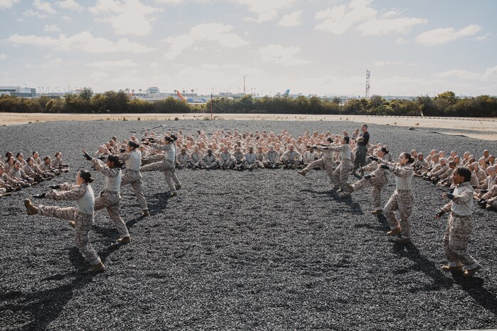 U.S. Marine Corps Martial Arts Instructor, Staff Sgt. Jacob Sinclair, with Support Battalion, Recruit Training Regiment, instructs recruits with Lima Company, 3rd Recruit Training Battalion, on how to properly conduct dynamic warm-ups before a Marine Corps Martial Arts Program class at Marine Corps Recruit Depot San Diego, California, Oct. 29, 2024. MCMAP aims to strengthen the mental and moral resiliency of recruits and Marines through realistic combative training, warrior ethos studies, and physical hardening. (U.S. Marine Corps photo by Cpl. Sarah M. Grawcock)