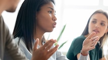 A female college student explaining a topic to other students during a meeting