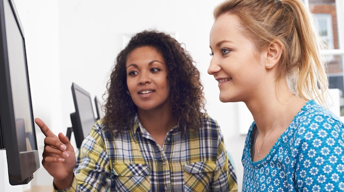 Two high school students looking at a computer and one is pointing to data on the screen