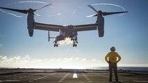 A U.S. Navy Sailor attached to the Expeditionary Sea Base (ESB) 6 USS John L. Canley watches a U.S. Marine Corps MV-22B Osprey prepare to land during a deck landing qualification training on the ship as part of exercise Warrior Voyage, off the coast of the island of O'ahu, Hawaii, Oct. 10, 2024.