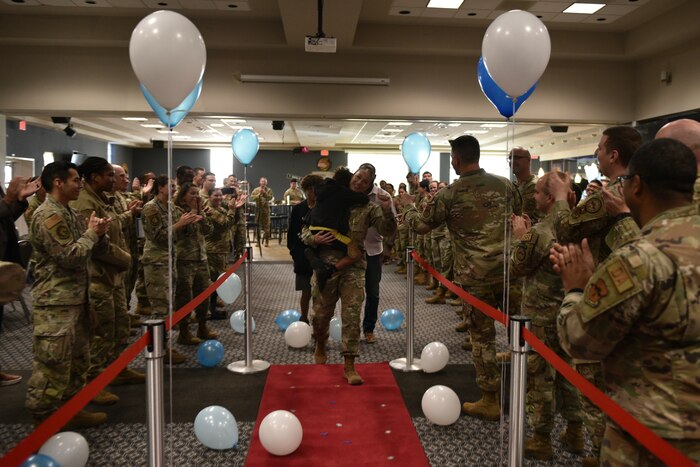 U.S. Air Force Chief Master Sgt. Select Jessica Thompson, 17th Force Support Squadron senior enlisted leader, walks down the red carpet with her family as members of the 17th training Wing applaud her during the Chief Release Party at the Powell Event Center, Goodfellow Air Force Base, Texas, Nov. 18, 2024. Thompson was one of 503 personnel selected for promotion to chief master sergeant in the 2024 promotion cycle. (U.S. Air Force photo by 1st Lt. Harris Hillstead)