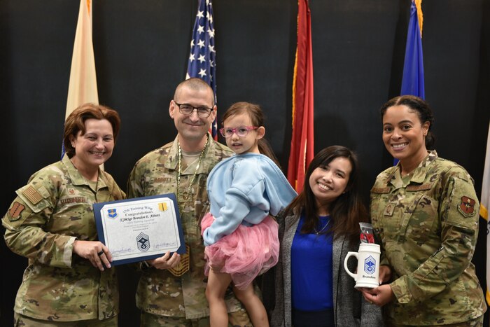 U.S. Air Force Col. Angelina Maguinness, 17th Training Wing commander, and Chief Master Sgt. Khamillia Washington, 17th TRW command chief, present a certificate of promotion and mug to Chief Master Sgt. Select Brandon Abbott, 316th Training Squadron operations superintendent, and his family during the Chief Release Party at the Powell Event Center, Goodfellow Air Force Base, Texas, Nov. 18, 2024. Abbott was one of 503 personnel selected for promotion to chief master sergeant in the 2024 promotion cycle. (U.S. Air Force photo by 1st Lt. Harris Hillstead)