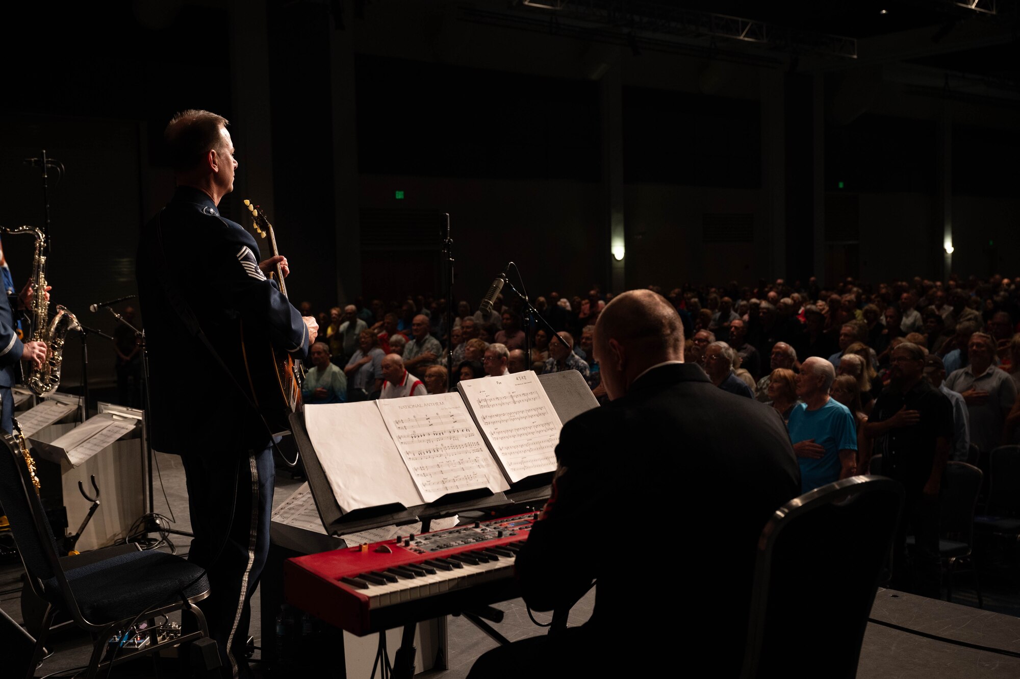 U.S. Air Force Senior Master Sgt. Geoff Reecer, guitarist with the USAF Band, U.S. Navy Chief Musician Brandon May, pianist with the U.S. Naval Academy Band, and members of the Airmen of Note, play “The Star-Spangled Banner” as members of the crowd stand during a performance in the Airmen of Note Fall 2024 tour in Punta Gorda, Fla., Nov. 13, 2024. The Airmen of Note’s mission, as a part of the U.S. Air Force Band, is to honor those who have served, inspire American citizens to heighten patriotism and service, and to connect the global community on behalf of the U.S. Air Force and the United States. The Airmen of Note consists of 17 active duty musicians and one vocalist stationed at Joint Base Anacostia-Bolling, Washington, D.C. (U.S. Air Force photo by Hayden Hallman)