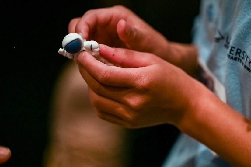 Close-up of a youth's hands holding a toy astronaut.