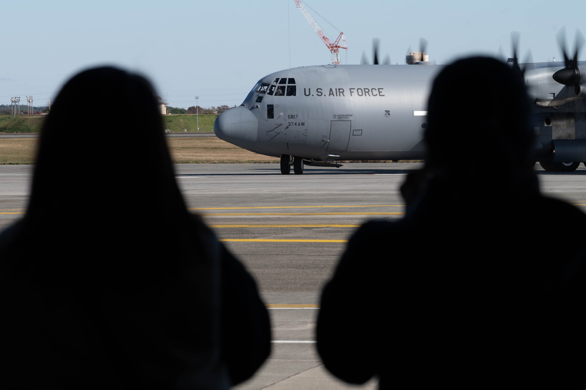 People watch a plane taxi on the runway.