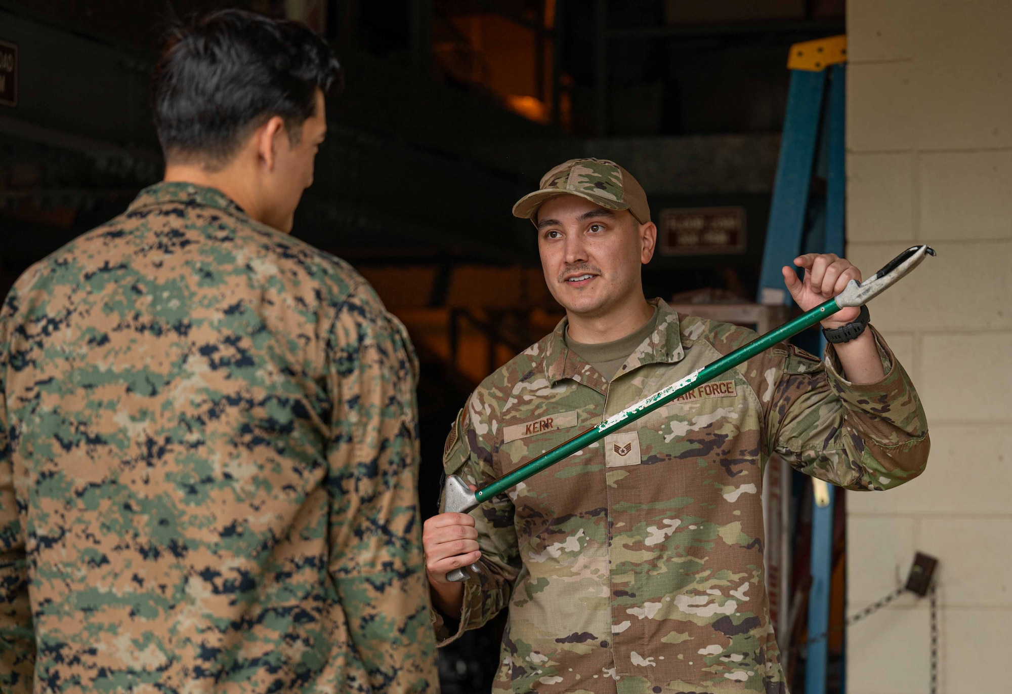 U.S. Air Force Staff Sgt. Jonathan Kerr, 18th Civil Engineer Squadron pest management non-commissioned officer in charge, right, and U.S. Navy Seaman Zavier Jae Wallace, 3d Medical Battalion preventative medicine technician, discuss the proper way to use snake tongs during a subject matter expert exchange at Kadena Air Base, Japan, Nov. 20, 2024.