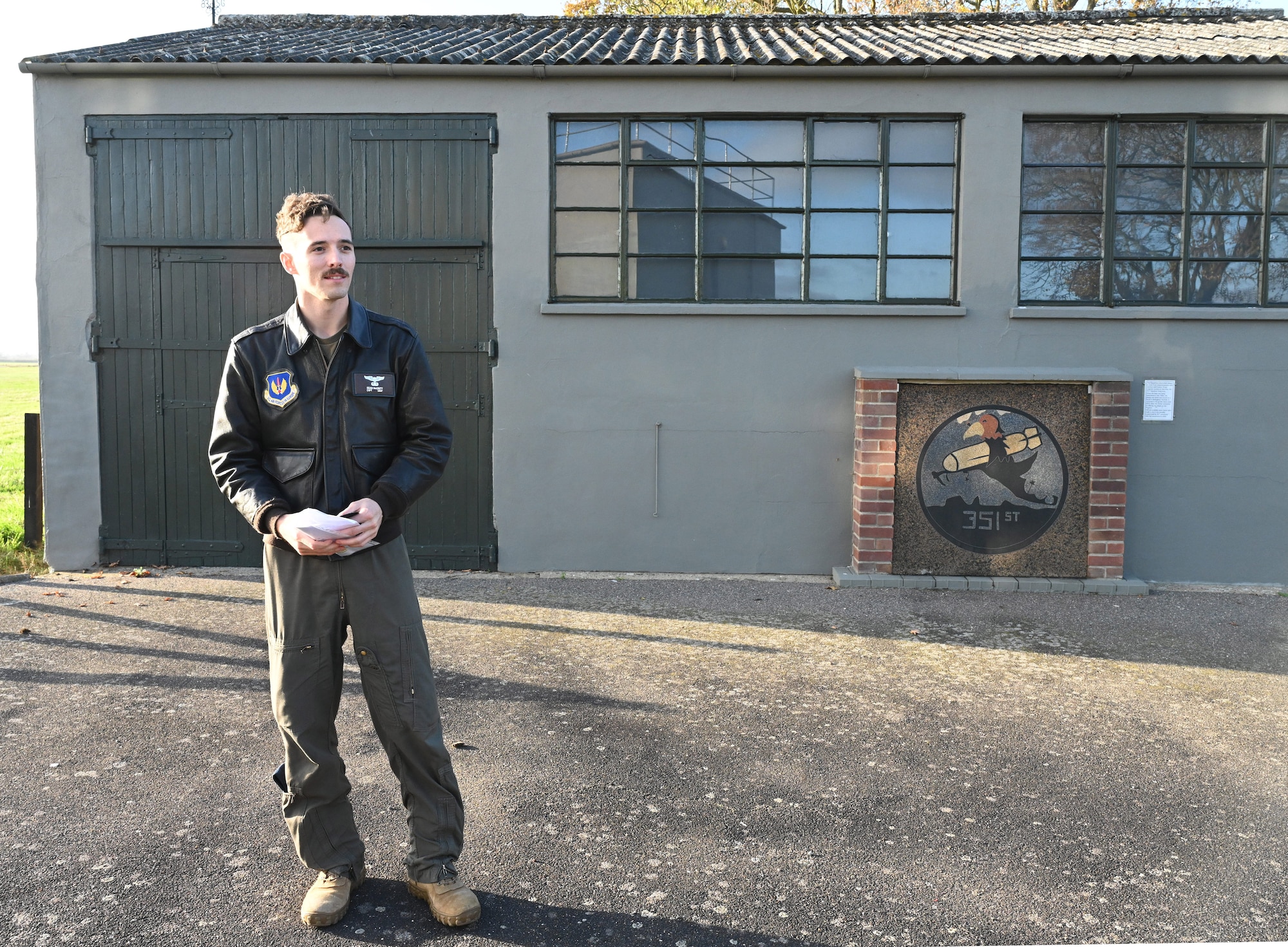 U.S. Air Force Capt. Sean McGinty, 351st Air Refueling Squadron pilot, addresses Airmen from his squadron and volunteers from the 100th Bomb Group Memorial Museum at the start of a patching ceremony at Thorpe Abbotts, Norfolk, England, Nov. 15, 2024. Pilots and boom operators received their heritage patch once they completed mission-certification training. Once MCT is completed, aircrew are fully certified on various mission sets and nuances that come with operating in the area of responsibility. (U.S. Air Force photo by Karen Abeyasekere)