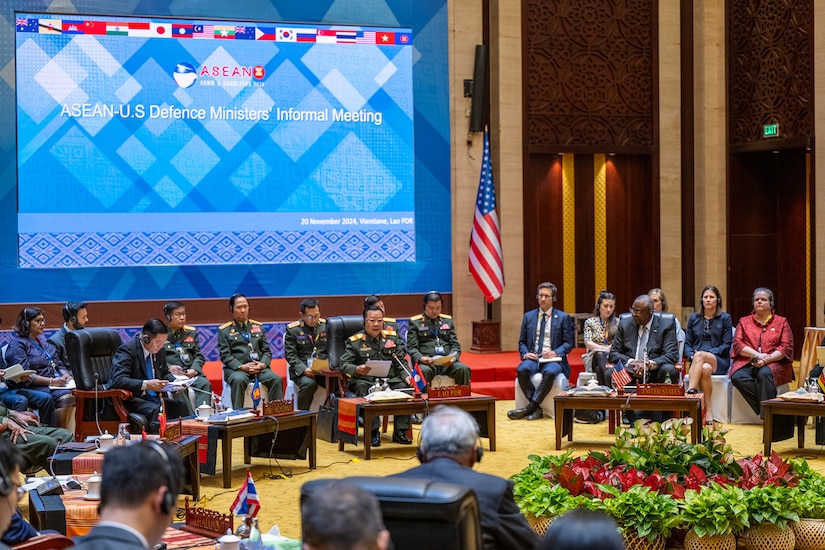 A group of men and women are seated in a conference room.