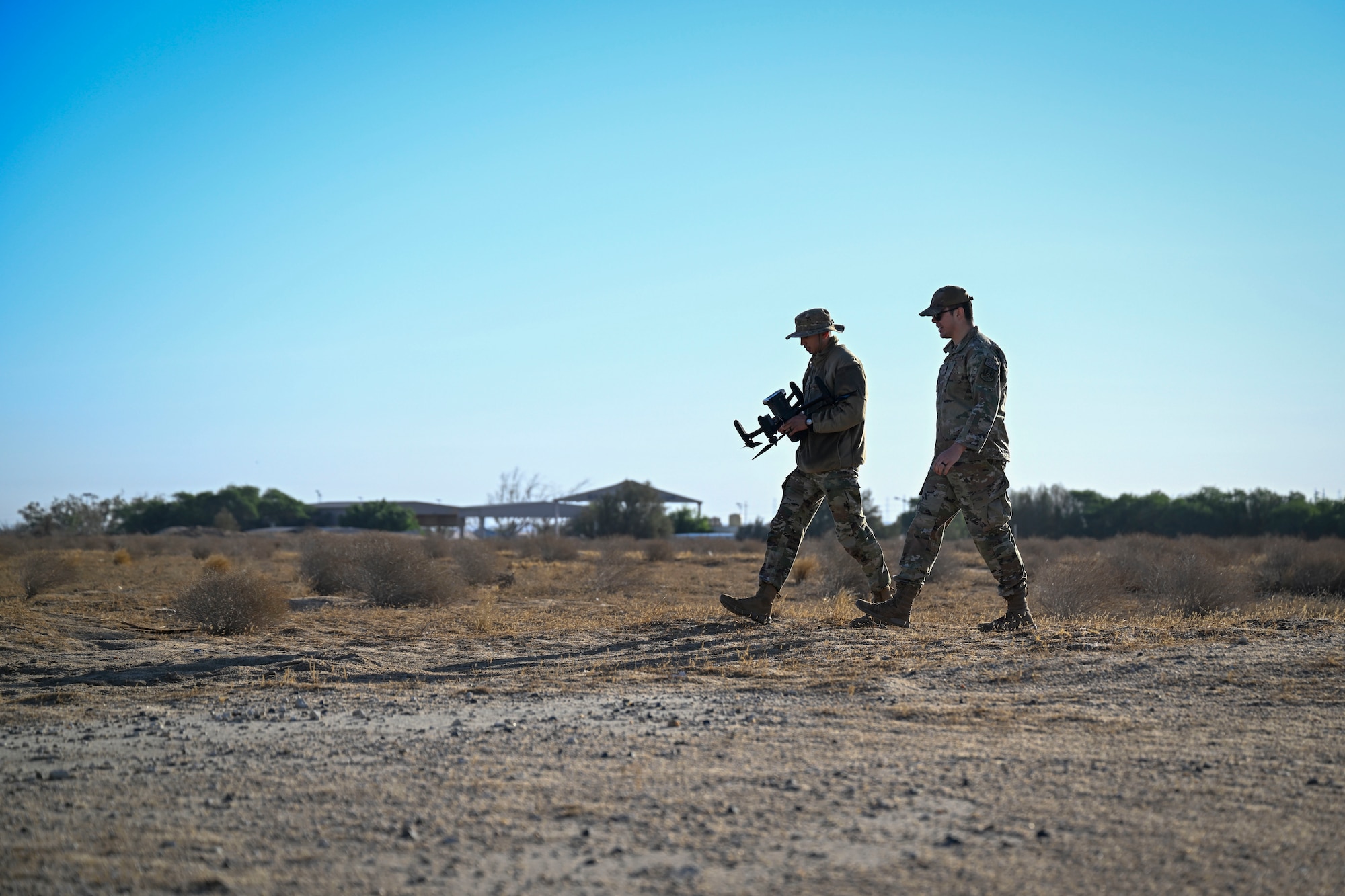 Two Airmen walk across a field.