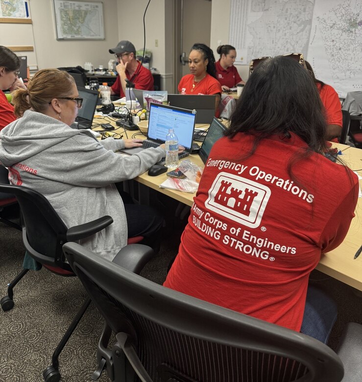 Photo of USACE Emergency Response workers sitting at a table working on laptops.