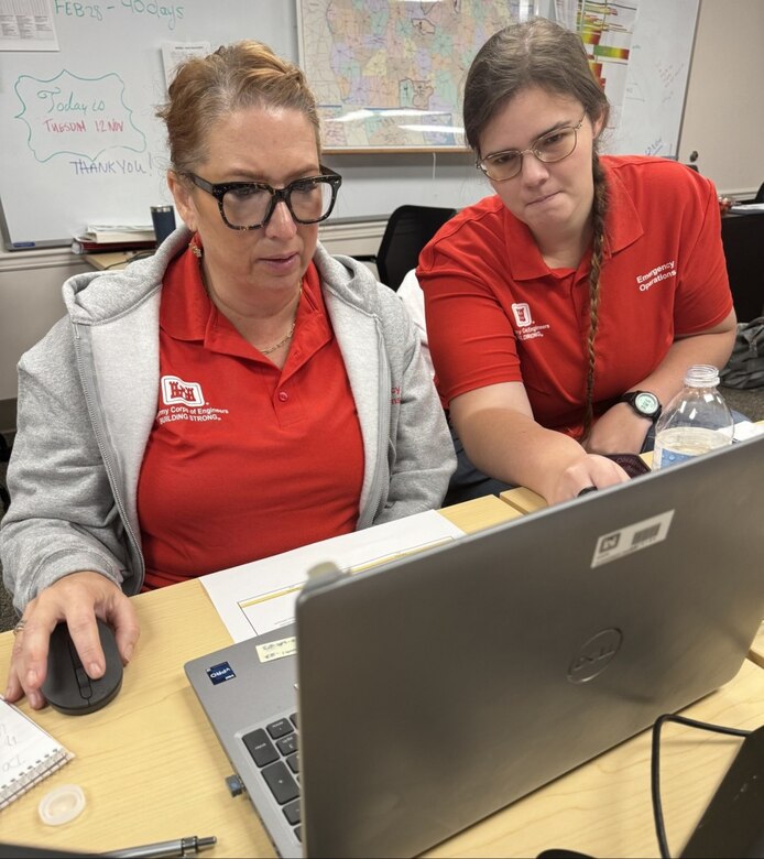 Photo of two women wearing red USACE shirts working on a laptop