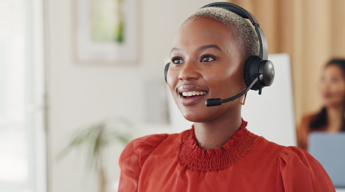 A black woman wearing a headset while working at her desk in her office