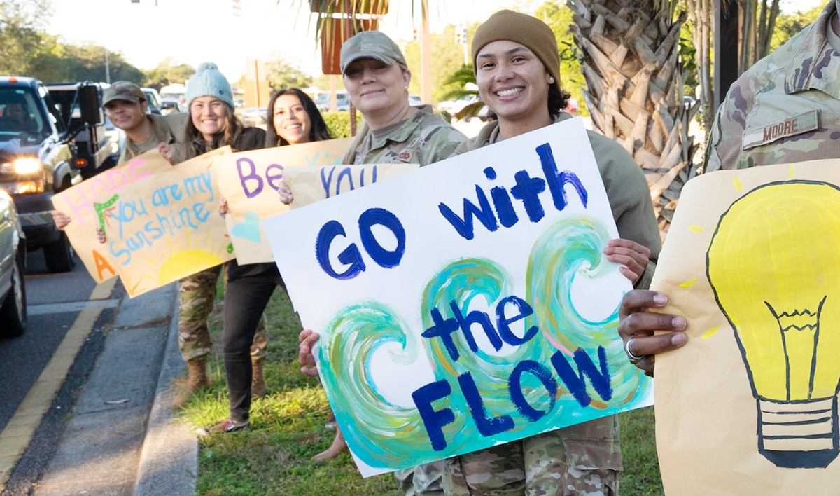 Team Eglin volunteers greet people with motivational signs by the gates.
