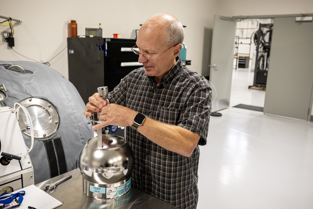 A man adjusts the top of a round metal container.