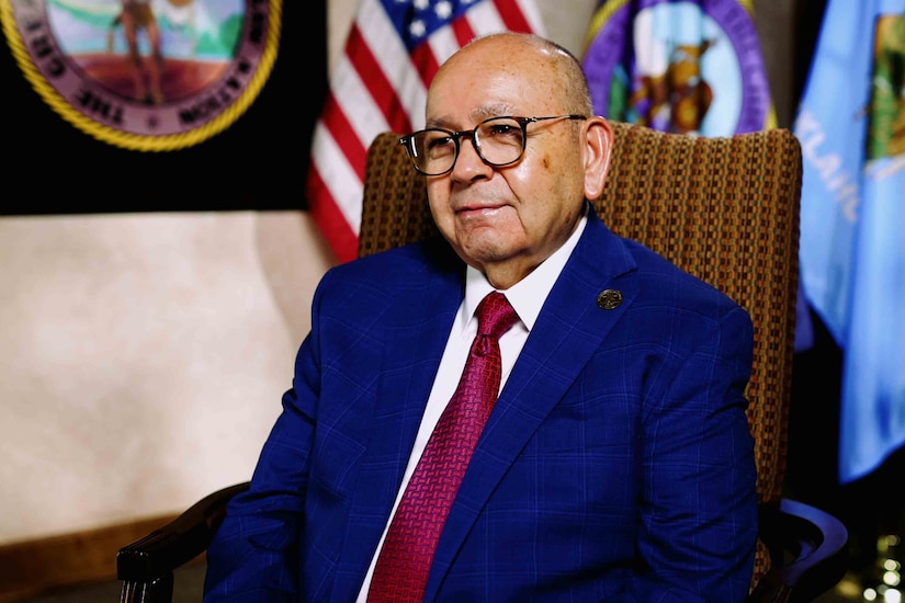 A civilian wearing a suit sits in a chair.