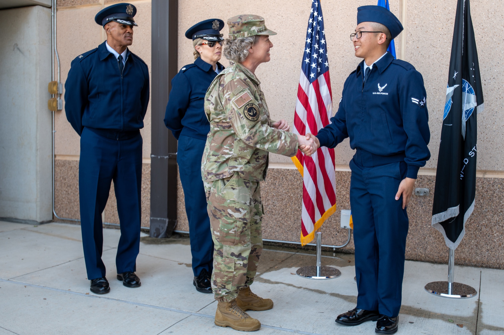 Brig. Gen. Amy Bumgarner, Air Force Office of Special Investigations commander, presents a coin to Airman Joe Pham, Basic Military Training graduate, with the overall best score during training at Joint Base San Antonio-Lackland, Texas, Nov. 6, 2024. (U.S. Air Force photo by Thomas Brading)
