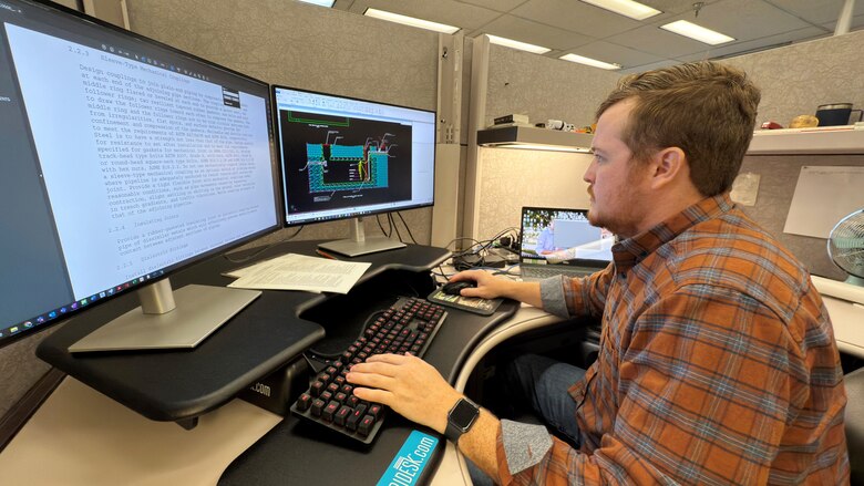 Nate Brock, civil engineer in the Civil Site and Survey Section, and Geotechnics Branch, reviews the design for a wastewater lift station for the Chickamauga Lock Replacement Project at his desk Nov. 19, 2024, in Nashville, Tennessee. The U.S. Army Corps of Engineers Nashville District recently selected him as its employee of the month for September 2024. (USACE Photo by Lee Roberts)