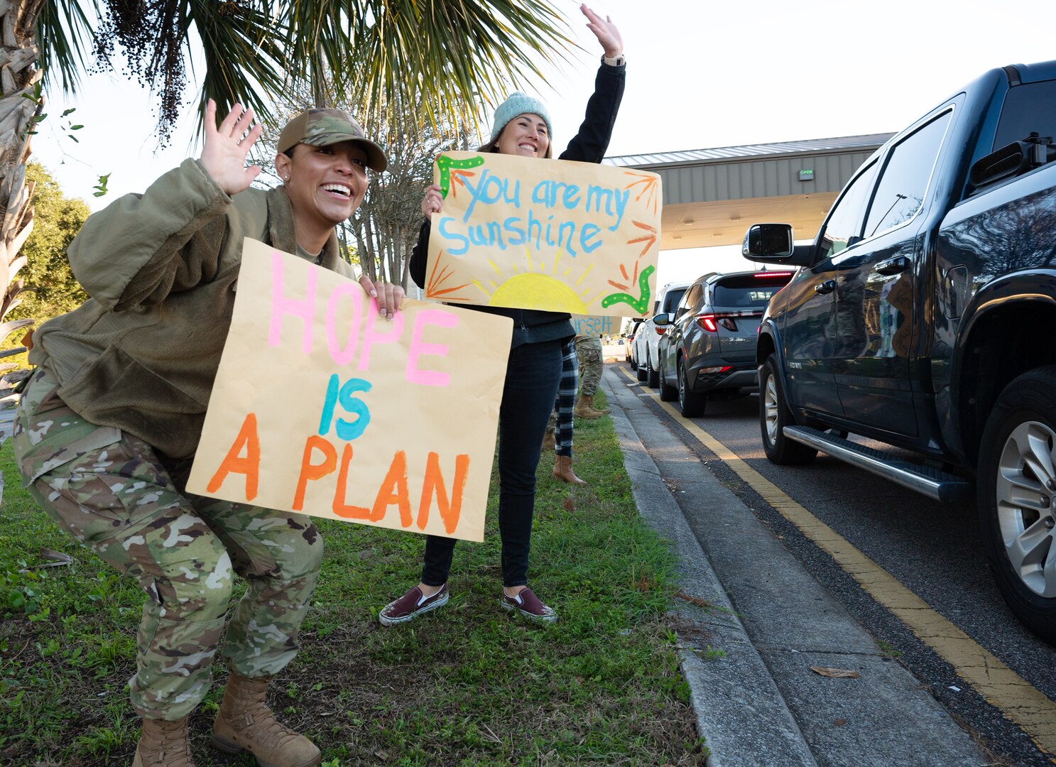 Team Eglin volunteers greet people with motivational signs by the gates.