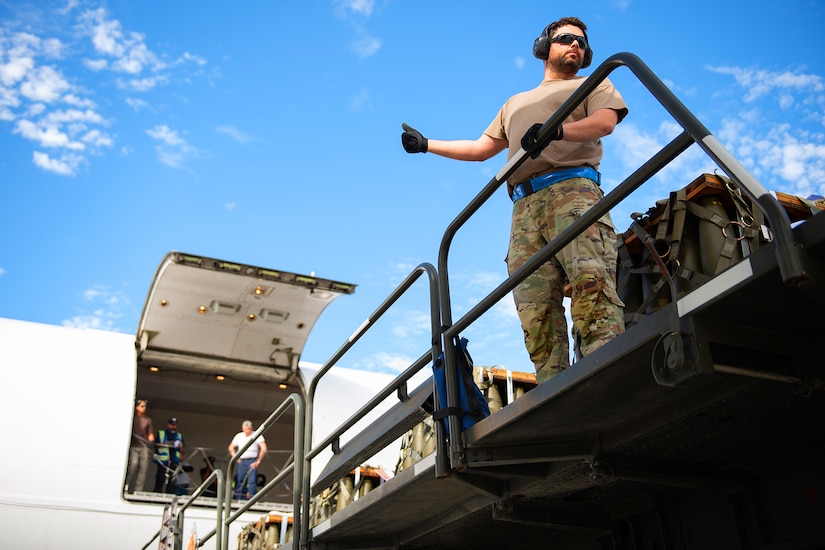 An airman provides a thumb up to people watching from an open aircraft.