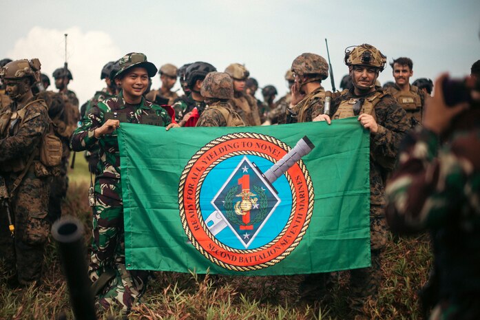 U.S. Marine Corps 1st Sgt. Chris Smith, right, company first sergeant for 2nd Battalion, 7th Marine Regiment, attached to Marine Rotational Force-Southeast Asia, holds a unit flag alongside an Indonesian Marine with 10th Marine Infantry Battalion, Indonesian Korps Marinir, after conducting a coastal defense exercise during Keris Marine Exercise (MAREX) 2024 in Indonesia, Nov. 15, 2024. Keris MAREX is a bilateral exercise conducted by the U.S. Marine Corps and Korps Marinir Republik Indonesia, to strengthen relationships as military partners and increase interoperability among participating forces in the advancement of a Free and Open Indo-Pacific.