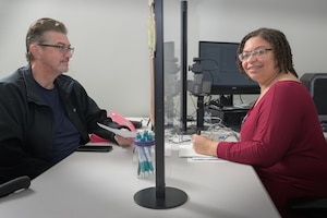 DLA Security Assistant Verifying Official Patricia Lily assists a customer inside the McNamara Headquarters Complex Pass and Identification Card at DLA Headquarters in Fort Belvoir, Virginia