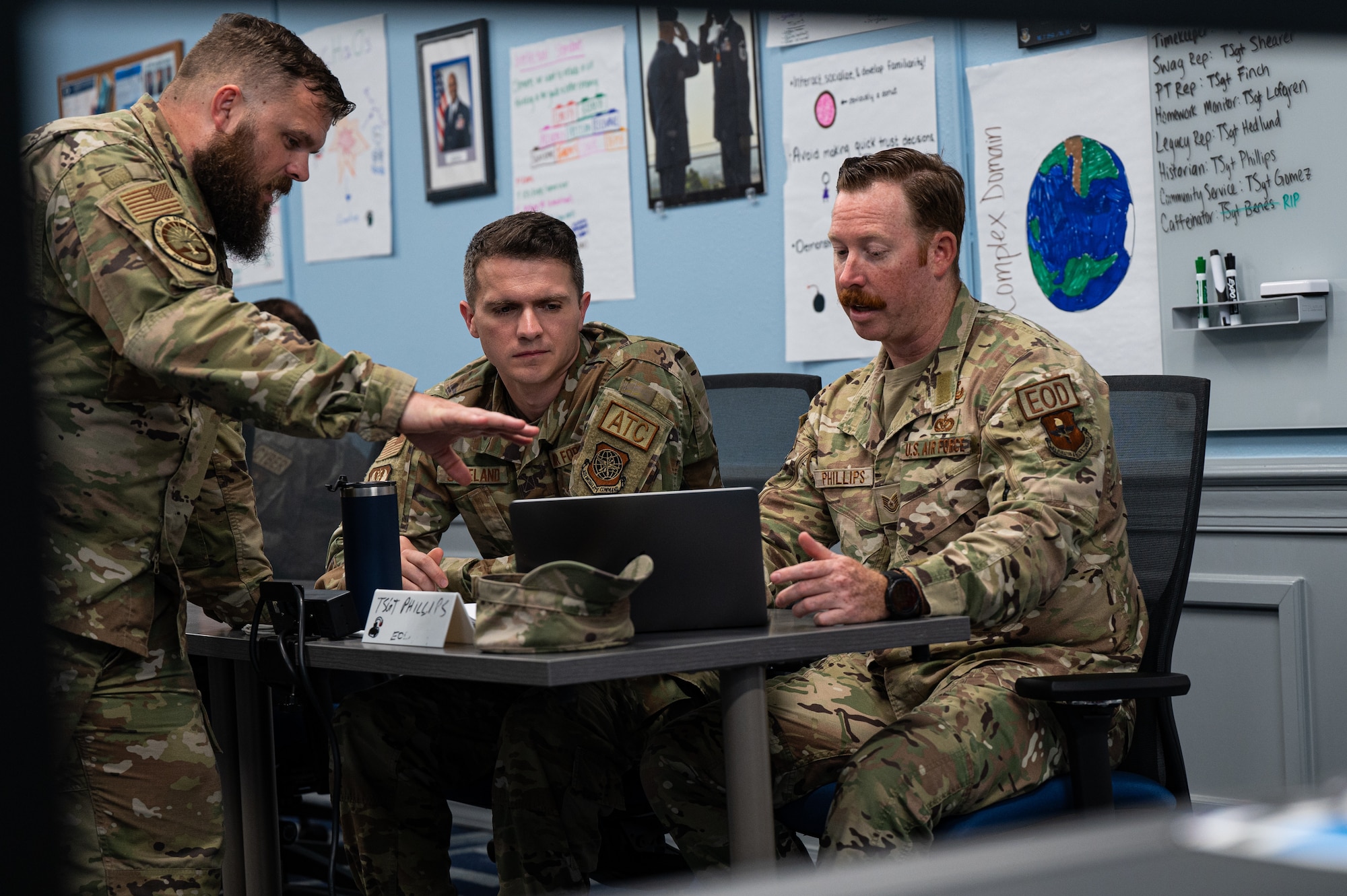 Airmen discuss presentation slides before presenting the slides to the class and instructor