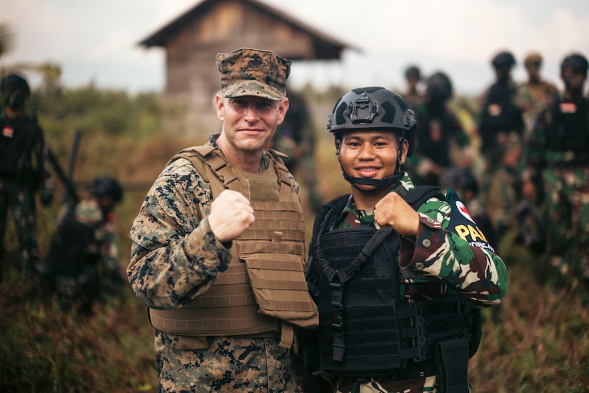 A U.S. and Indonesian marine pose for a photo with fists clenched.