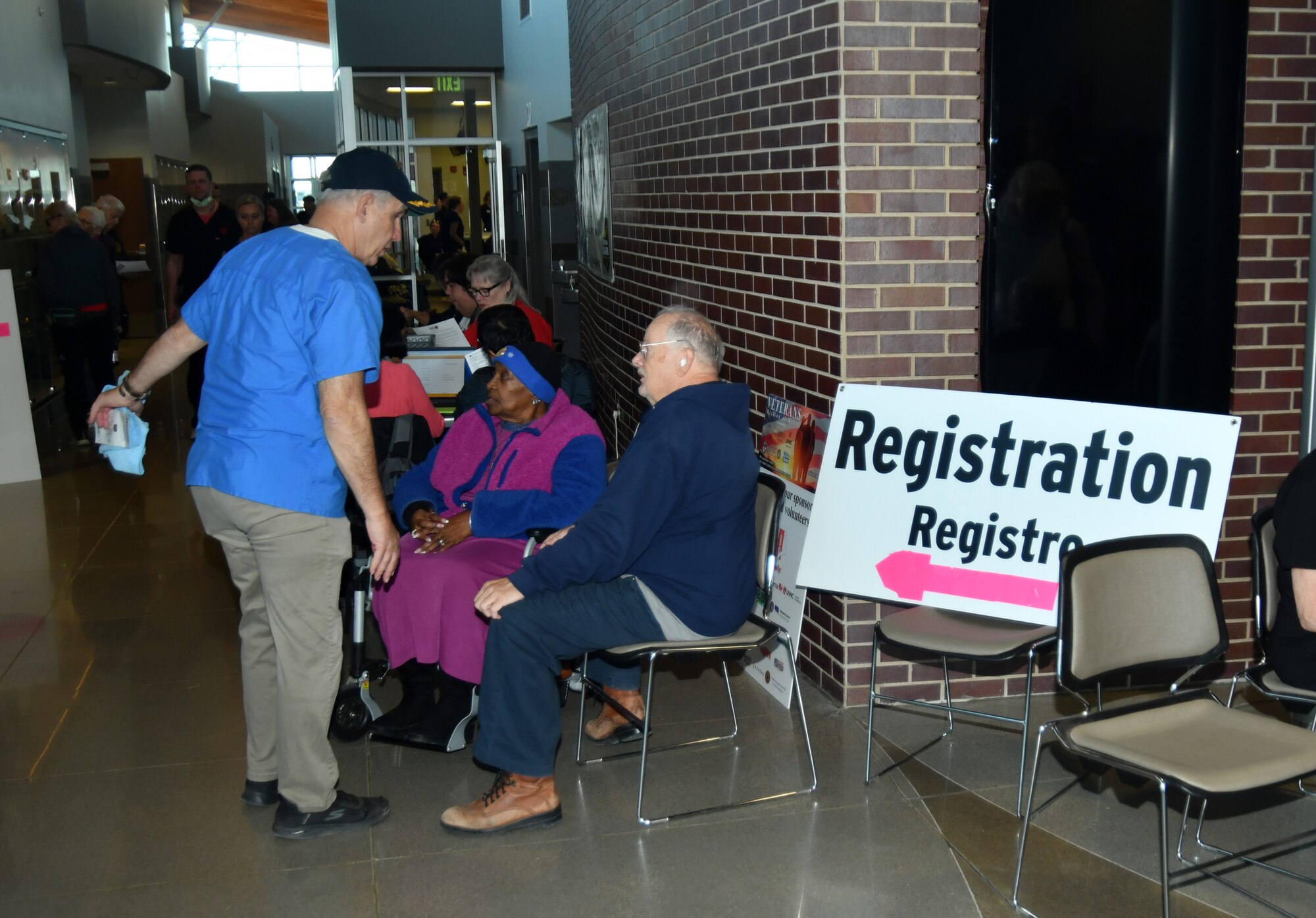 Man standing and talking to couple sitting down at registration table for an event
