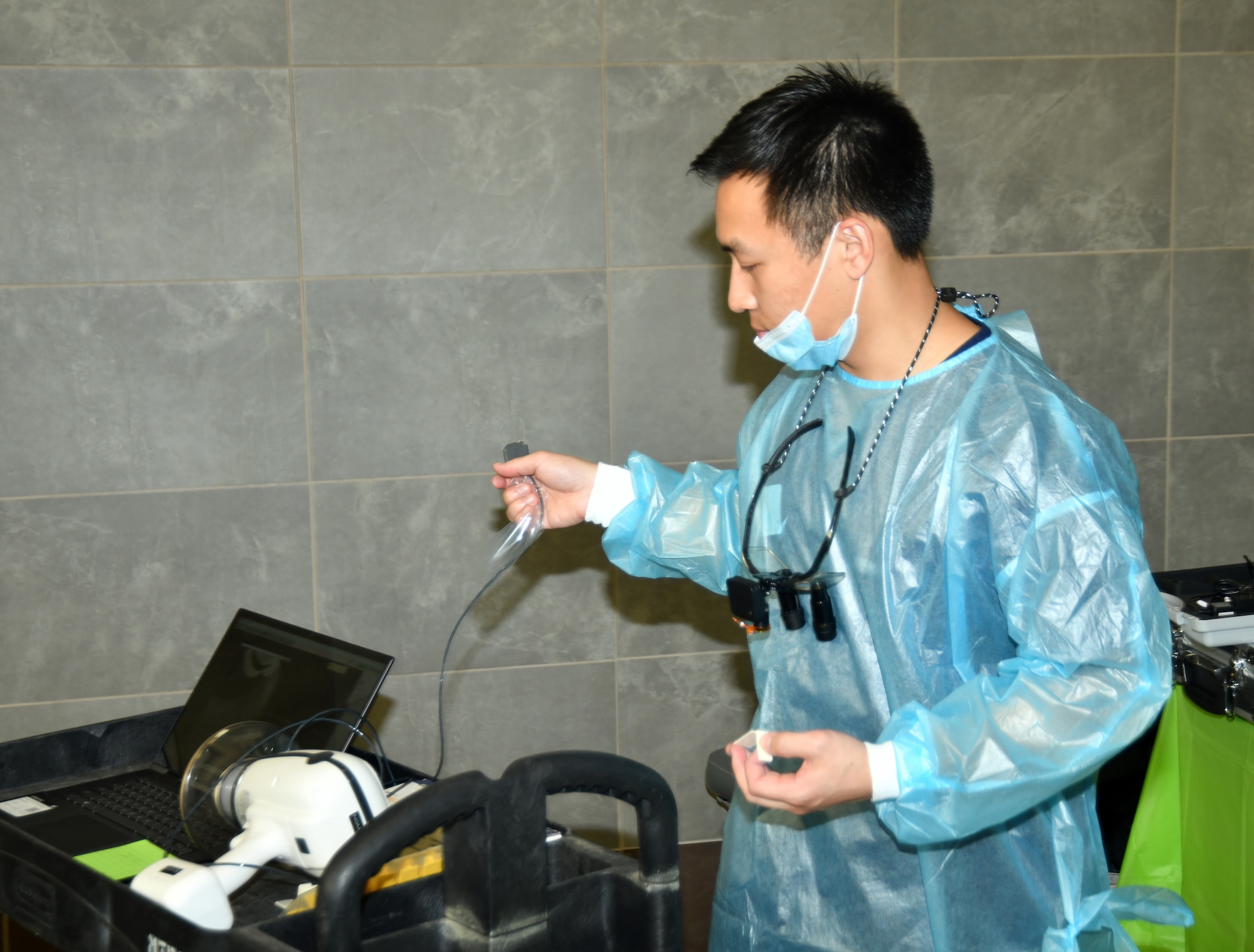 Dr. preparing hand held x-ray machine in blue protective jacket
