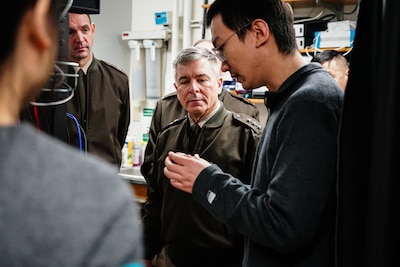 A uniformed military officer looks at a device in a college student's hands.