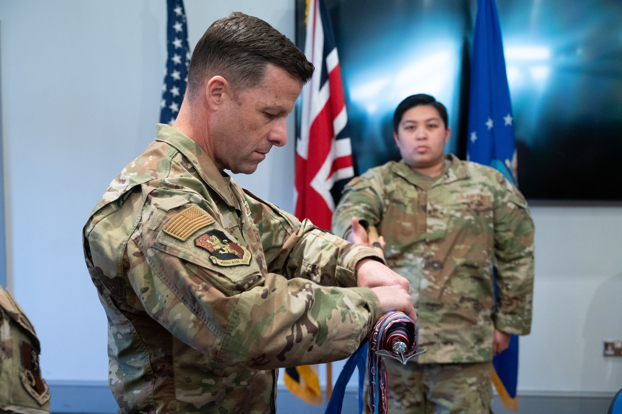 A commander rolls up a decommissioned flag