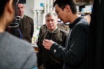 A uniformed military officer looks at a device in a college student's hands.
