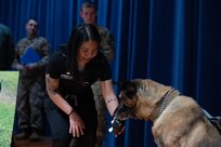 Dog receives treat on stage during his retirement ceremony.
