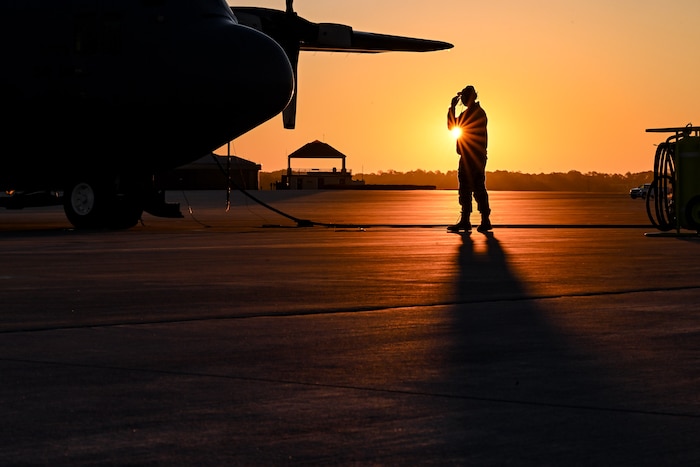 The sun rises behind a Citizen Airman assigned to the 910th Maintenance Squadron on the flightline at Dobbins Air Reserve Base, Georgia, Nov. 16, 2024.