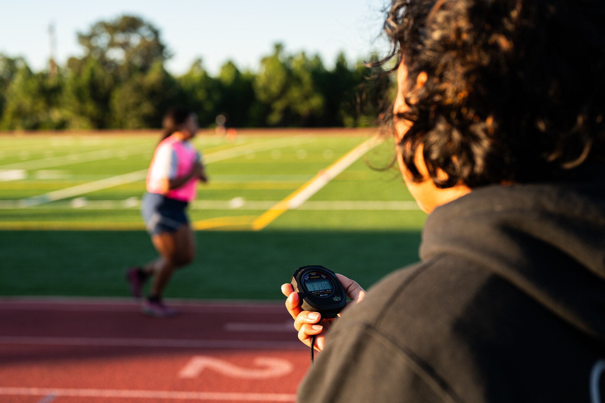 An instructor from the Airey NCOA records run times of Airmen during a mock physical assessment test