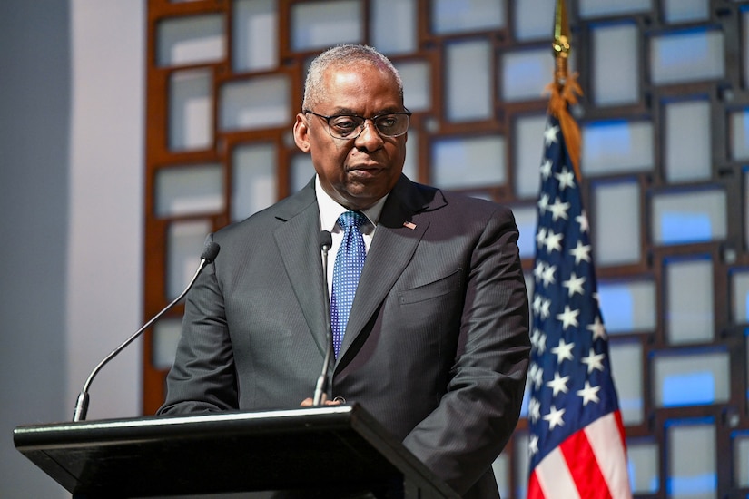 A man wearing business attire stands at a lectern.