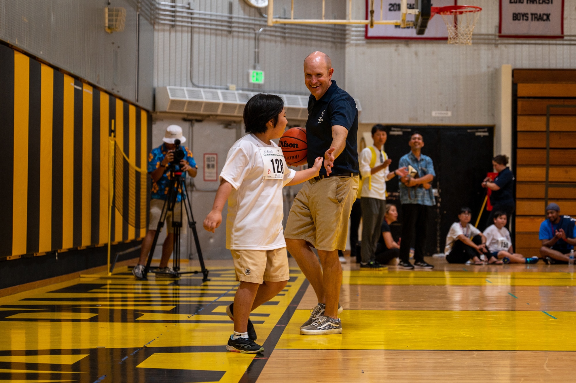 A participant high-five with military service member on a basketball court.