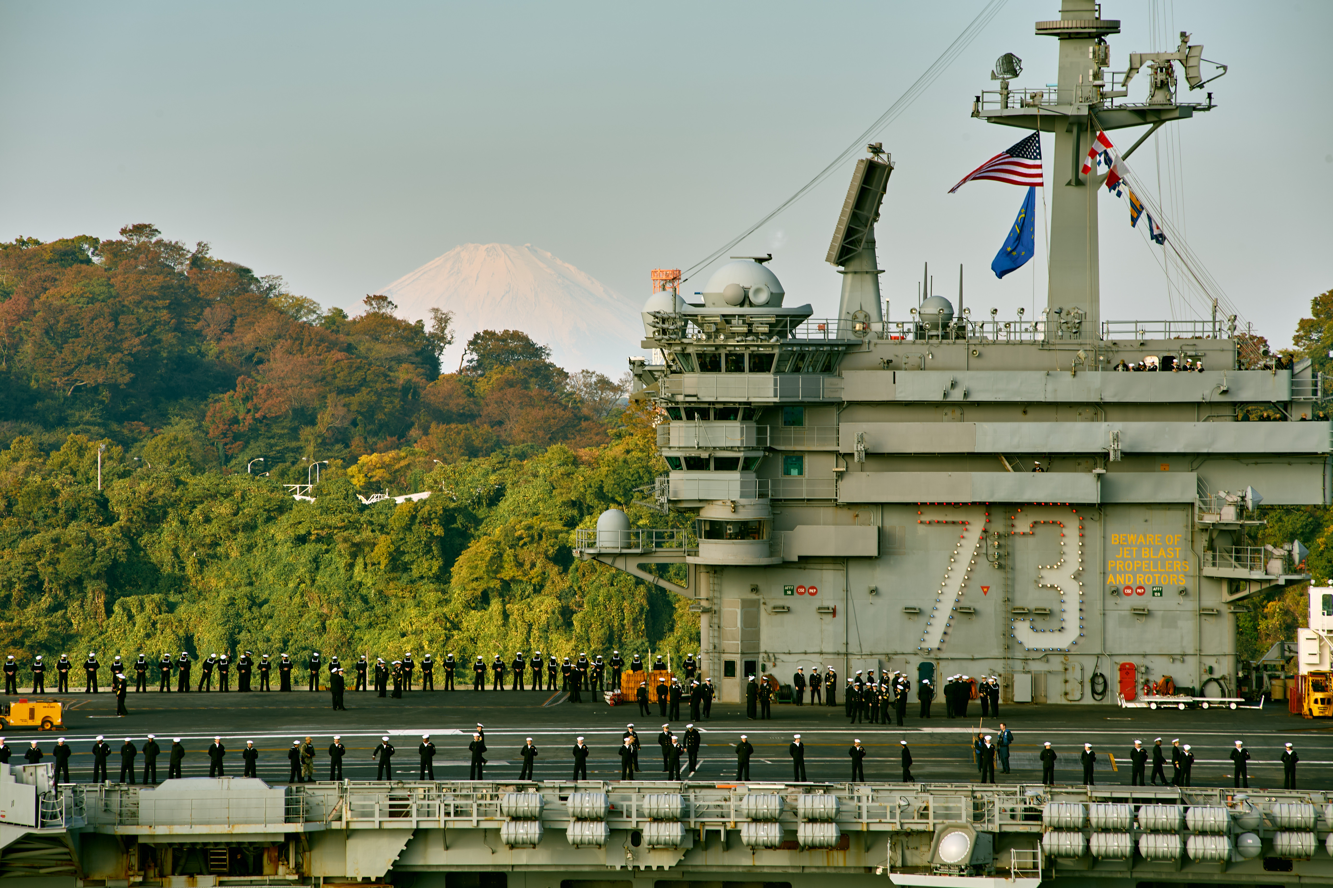 Sailors assigned to the Nimitz-class aircraft carrier USS George Washington (CVN 73), man the rails on the flight deck as the ship pulls into Commander, Fleet Activities Yokosuka. George Washington is 7th Fleet's premier forward-deployed aircraft carrier, a long-standing symbol of the United States' commitment to maintaining a free and open Indo-Pacific region, while operating alongside Allies and partners across the U.S. Navy's largest numbered fleet.