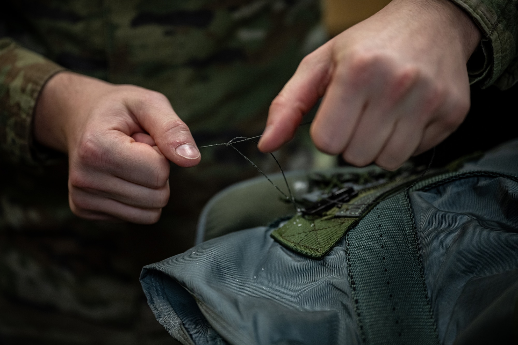 An Airman sews a life saving vest