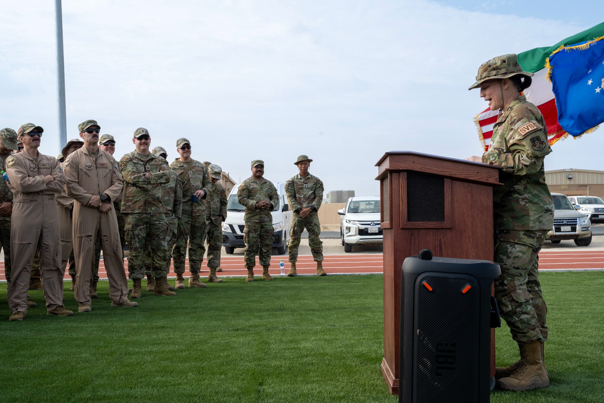 A commander speaks at a lectern on the right during a ceremony to open the base's new running track and field.