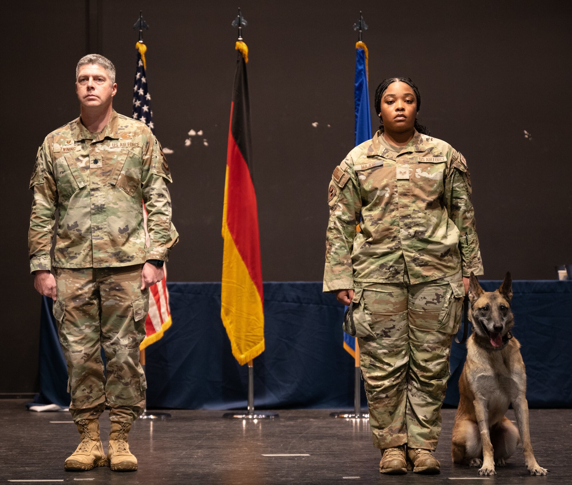 People stand on stage with military working dog