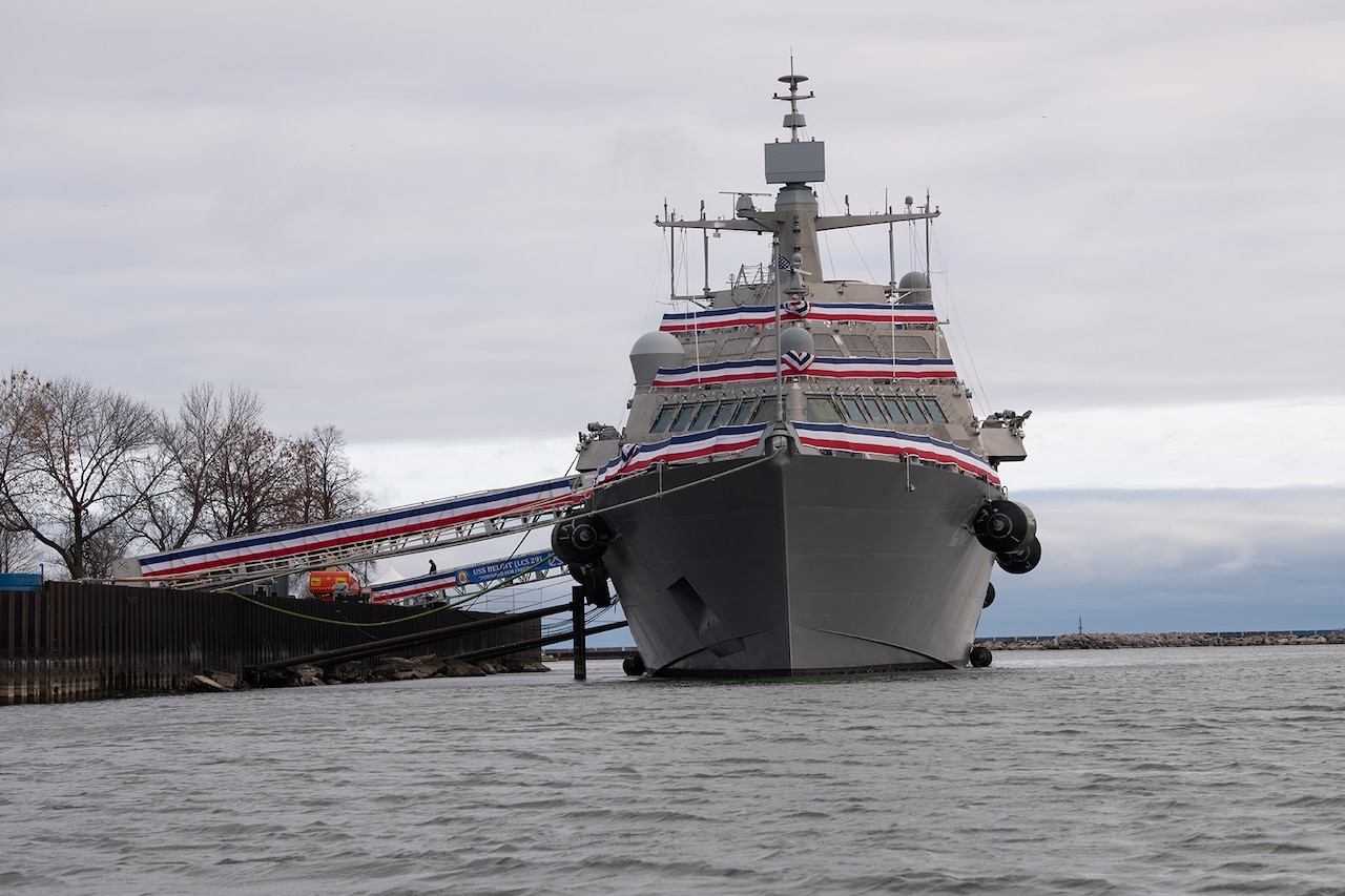 A Navy vessel is docked at port during a cloudy day.