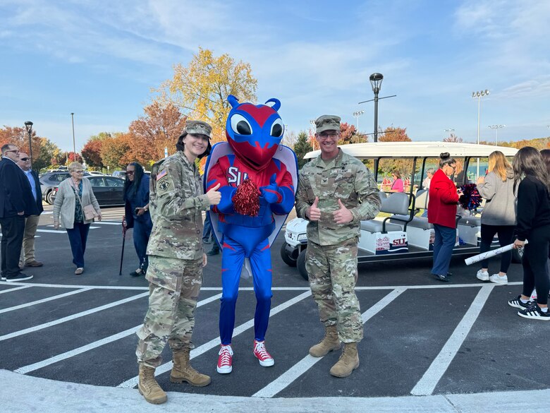 Two people posing on either side of the school mascot.