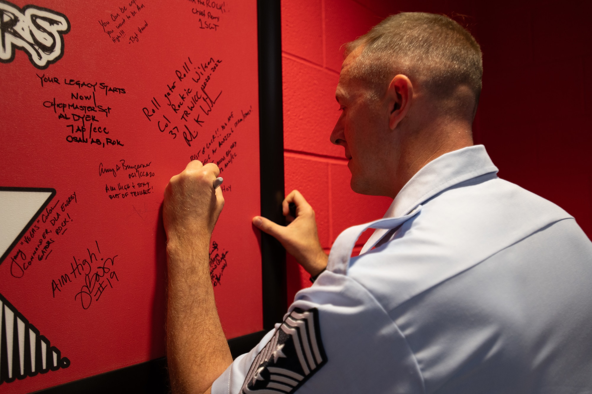 Chief Master Sgt. James Hoy, AFOSI command chief, adds his signature to a wall at the 320th Training Squadron dormitories, Joint Base San Antonio-Lackland, Texas, Nov. 7, 2024. The wall, signed by senior leaders who have previously toured the dorms, commemorates Hoy’s visit as AFOSI’s top enlisted member. (U.S. Air Force photo by Thomas Brading)