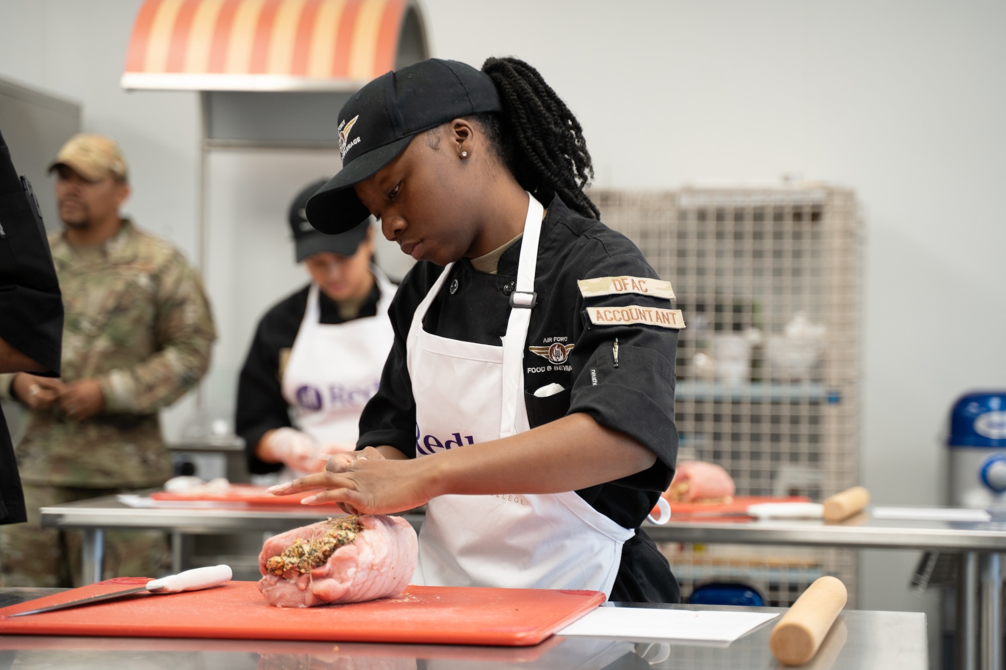 Airman 1st Class Grace Tindal, 22nd Force Support Squadron food service journeyman, prepares a stuffed pork chop using a new recipe at the Redler Institute of Culinary Arts Nov. 19, 2024, in Andover, Kansas. The recipe was adapted by the culinary institute’s lead chef to add a pesto sauce to an existing recipe at the Chisholm Trail Inn Dining Facility (DFAC). The DFAC was awarded the 68th annual Air Force John L. Hennessy Award earlier this year, as the top dining facility in the Air Force, and has partnered with the Redler Institute of Culinary Arts to further the quality of its operations and dishes while also broadening the experience and expertise of the dining facility staff. (Courtesy Photo)