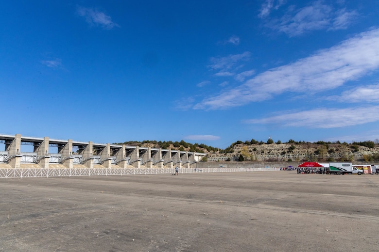 Grey concrete in the foreground with blue sky in the background and a few trucks to the right.