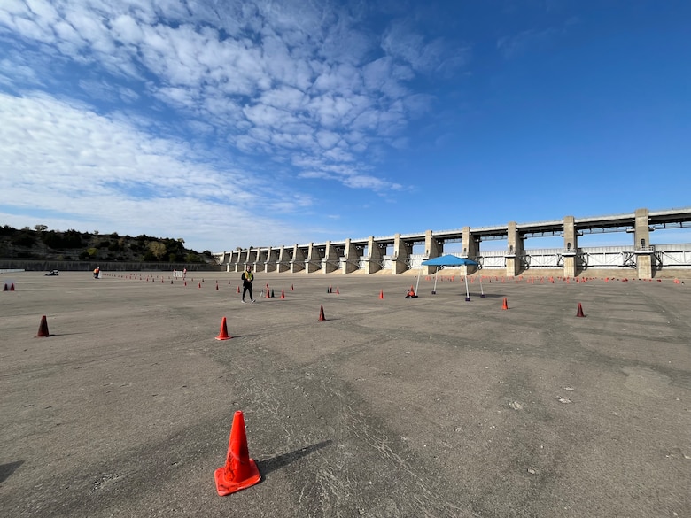 Orange traffic cones sit on a large slab of grey concrete with a blue sky in the background.